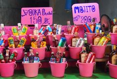 many pink buckets filled with different types of drinks and condiments for sale