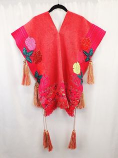 90s Chiapas poncho, handwoven Pok'u'ul, floral poncho with tassels, neon flowers and butterflies, tasseled poncho, Mexican maximalist boho Immerse yourself in the vibrant culture and craftsmanship of Chiapas with this stunning 90s Chiapas Poncho, a handwoven Pok'u'ul masterpiece. This traditional poncho, made on a pedal waist loom, embodies the rich heritage of Mexican textile artistry. Originally designed for men in Chiapas, this versatile garment now celebrates gender fluidity, allowing anyone to experience its warmth and beauty. The poncho boasts a striking color palette between red and pink, creating a bold canvas for its intricate details. Hand-embroidered neon flowers and butterflies adorn the poncho, adding bursts of vibrant color that dance across the surface. The bottom hem is acc One Size Tassel Poncho For Spring, Handwoven Poncho Shawl For Festivals, Handwoven Festival Poncho Shawl, One Size Spring Poncho With Tassels, Spring Poncho One Size With Tassels, Spring Poncho With Tassels, Spring Poncho With Tassels One Size, Red Bohemian Poncho For Festival, Bohemian Shawl With Floral Embroidery For Festival