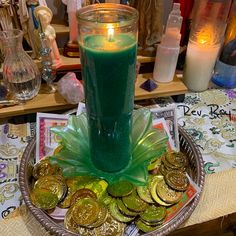 a green candle sitting on top of a plate filled with coins