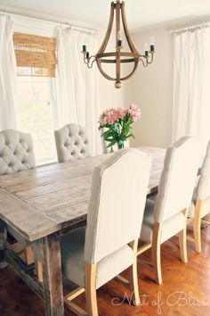 a dining room table with white chairs and a chandelier hanging from the ceiling