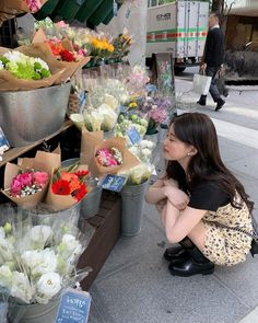 a woman kneeling down in front of flowers