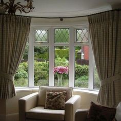 a living room filled with furniture next to a window covered in curtains and drapes