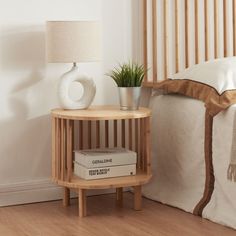 a table with two books and a lamp on it next to a bed in a room