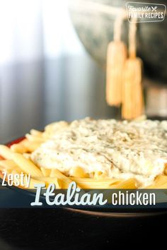 a pasta dish with cheese and sauce on the side, sitting on a black plate