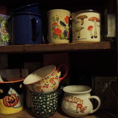 many different types of mugs are on the shelf