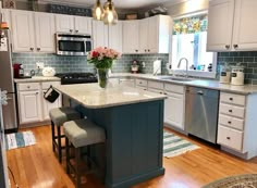 a kitchen with white cabinets and blue island