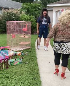 a woman walking down a sidewalk next to a pink bird cage