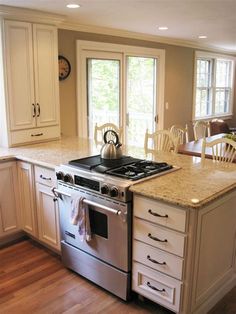 a stove top oven sitting inside of a kitchen next to a table with chairs on it