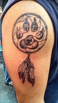 a man with a tattoo on his arm has a bear dream catcher in it's hand