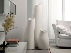 three white vases sitting on top of a table next to a couch