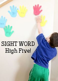 a little boy that is standing in front of a wall with handprints on it