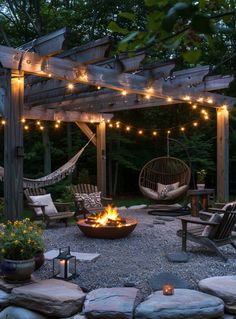 an outdoor fire pit surrounded by chairs and lights