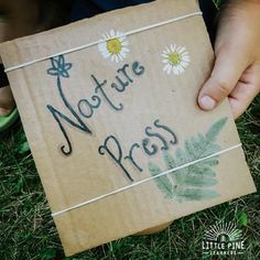 a person holding a sign that says noture press with daisies in the grass