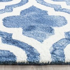 a blue and white area rug with an abstract design on the bottom, in front of a wood floor