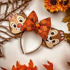 the ears of two cartoon mouses are decorated with autumn leaves