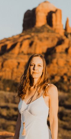 a woman standing in front of a mountain