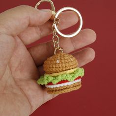 a small crocheted hamburger keychain is being held in someone's hand