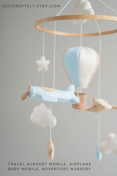 a baby mobile with an airplane and clouds hanging from it's sides, on a gray background