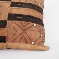 a brown and black pillow with decorative designs on it's side, sitting on a white surface