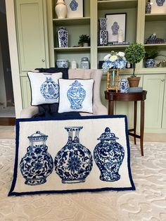 three blue and white vases sitting on top of a rug in front of a bookshelf