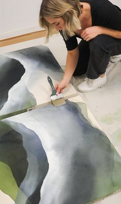 a woman is painting an image on the floor