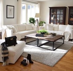 a living room filled with white furniture and lots of plants on top of the table