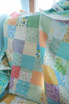 a patchwork quilt sitting on top of a couch next to a window in a room