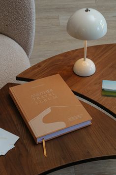 an open book sitting on top of a wooden table next to a lamp and papers