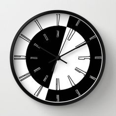 a black and white clock with roman numerals on the face is hanging on a wall