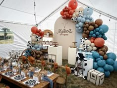 an outdoor party with balloons and decorations on the table, including cow - print napkins