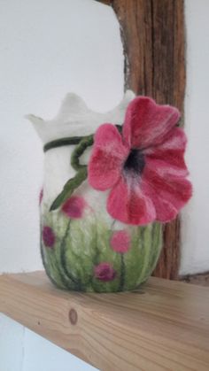 a vase with flowers painted on it sitting on a shelf next to a wooden wall