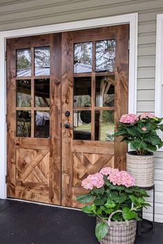 two potted flowers sitting on the front steps of a house next to a wooden door