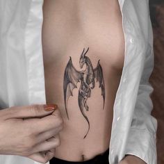 a woman with a dragon tattoo on her stomach is holding the other side of her chest