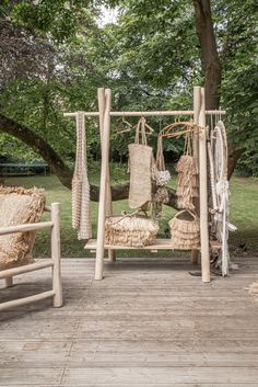 an outdoor area with two chairs and some baskets on the ground in front of trees