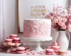 a pink cake and macaroons are sitting on a table next to a vase with flowers