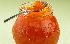 a spoon full of honey sitting on top of a glass jar filled with liquid and jelly