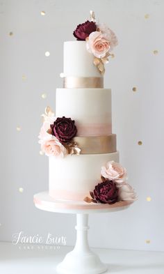 a three tiered wedding cake with pink and gold flowers on the top, in front of confetti sprinkles