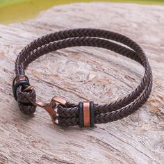 Braided by hand brown leather is used to form two strips that circle the wrist. Thai artisan Passaramon creates this wristband bracelet which exudes strength. It closes with an anchor-shaped clasp of copper-tone stainless steel. Adjustable Brown Copper Braided Bracelets, Adjustable Brown Leather Bracelet With Wrist Strap, Brown Leather Strap Bracelet, Brown Jewelry With Wrist Strap For Gift, Adjustable Brown Wristband With Bracelet Strap, Adjustable Brown Bracelet With Wrist Strap, Brown Leather Wrap Bracelet As Gift, Brown Leather Strap Wristband, Brown Leather Wrap Bracelet For Gift