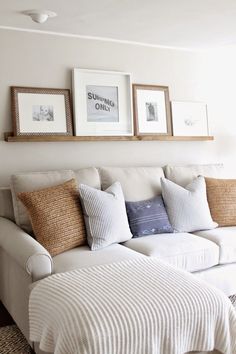 a white couch with pillows and pictures on the wall