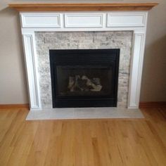 an empty room with a fireplace and wood floors