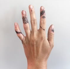 a person's hand with tattoos on it and two fingers in the shape of leaves