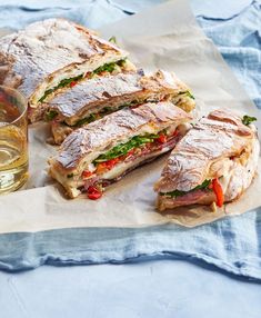 a cut in half sandwich sitting on top of a table next to a glass of water