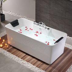 a white bath tub with red rose petals on the side and candles in front of it