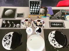 a table topped with plates covered in black and white artwork next to cups and saucers