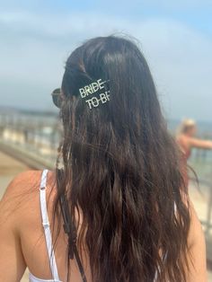 the back of a woman's head with two hair clips that say bride to be