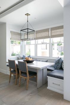 a dining room table and bench in front of two windows