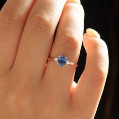 a woman's hand with a ring on it and a blue stone in the middle