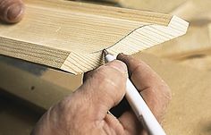 a person using a pencil to draw on wood