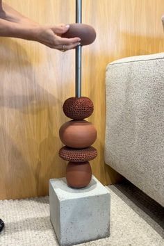 a person standing next to a pile of rocks on top of a white block in front of a wooden wall