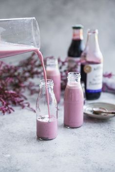 pink smoothie being poured into glass bottles